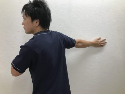 瑞穂市スタッフブログ壁を利用しての胸のストレッチの様子